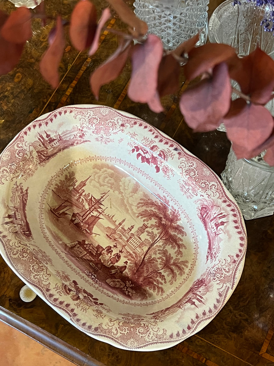 Antico Piatto da portata in ceramica olandese con decoro rosa a transfer raffigurante dei commercianti intenti a vendere un tappeto ad un nobile gentiluomo.  Misure 28x22x6 cm