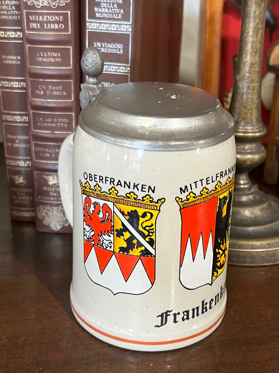 Boccale da birra tedesco in ceramica "Frankenkrug" un omaggio alla regione della Franconia in Germania. Realizzato in ceramica con una decorazione vivace con stemmi araldici che rappresentano le aree di Oberfranken, Mittelfranken, e Unterfranken, riccamente dettagliati con colori vividi.

Misure 13x10x15,5h cm