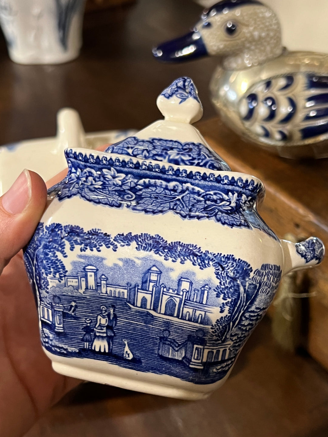  Zuccheriera in ceramica Mason's con motivo "Vista" in un intenso blu cobalto. Il disegno dettagliato presenta un paesaggio idilliaco che aggiunge un tocco di stile romantico e storico alla tua tavola. Ogni elemento, dalla maniglia sagomata al coperchio ornato, è stato creato con cura per offrire non solo un utile recipiente per lo zucchero, ma anche un vero gioiello decorativo per qualsiasi amante della ceramica d'epoca.&nbsp;

Misure 12,5x8x12,5 cm